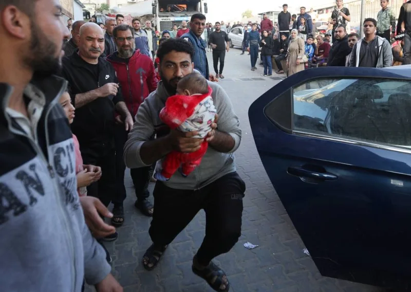 A man holds a baby as wounded Palestinians are rushed into Nasser hospital following Israeli strikes, in Khan Younis in the southern Gaza Strip, on Monday. REUTERS