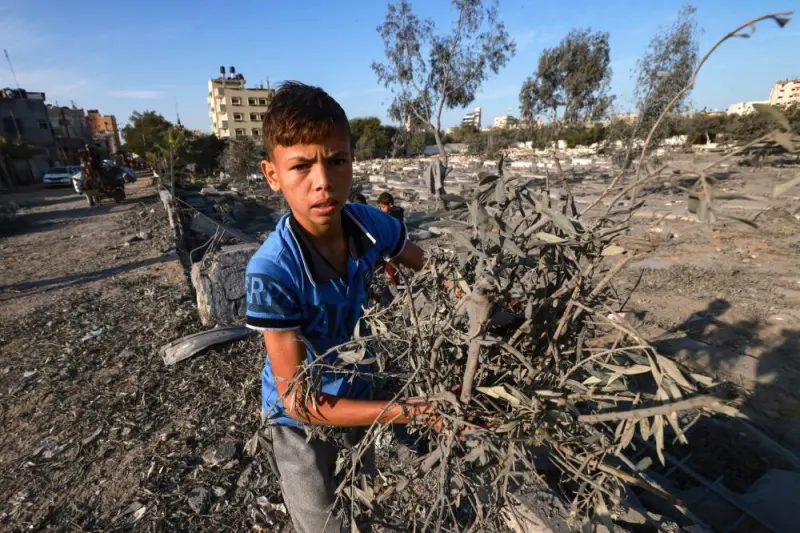 Palestinian boys collect wood near a cemetery damaged following Israeli air strikes in Rafah in the southern Gaza Strip early Monday. AFP
