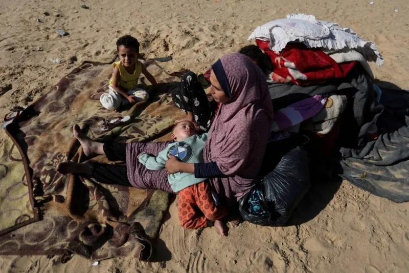 A woman sits with children, as displaced Palestinians, who fled their homes due to Israeli strike, shelter in a camp in Rafah, Wednesday.