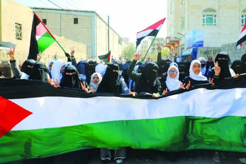 
Women and children stand behind a giant Palestinian flag during a protest in front of the UN office in Sanaa, Yemen, yesterday, in solidarity with the Palestinians. 