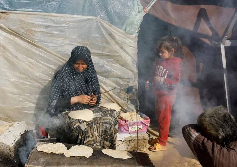 A child stands next to a cooking woman, as displaced Palestinians, who fled their houses due to Israeli strikes, shelter in a tent camp near the border with Egypt, in Rafah in the southern Gaza Strip, on Monday. REUTERS