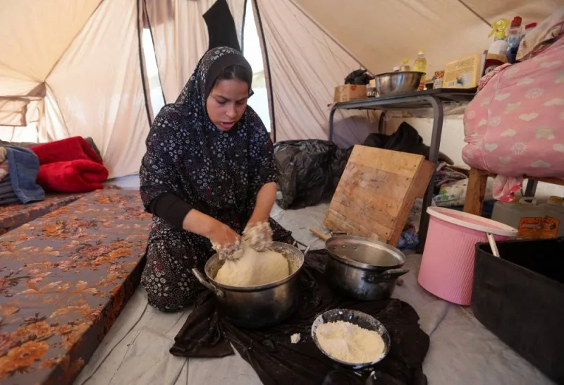 A displaced Palestinian, who fled her house due to Israeli strikes, prepares a meal as she shelters in a tent camp, in Khan Younis in the southern Gaza Strip, on Monday. REUTERS