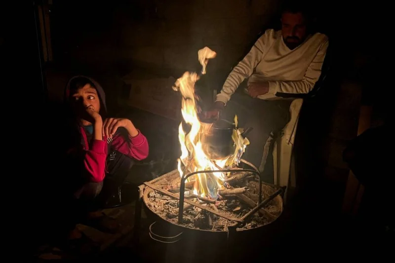 Palestinians sit around a fire during a power cut, in Rafah, in the southern Gaza Strip, on Monday. REUTERS