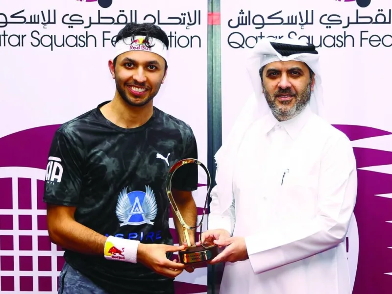 Qatar’s Abdullah al-Tamimi receives the winner’s trophy from Qatar Tennis, Squash and Badminton Federation secretary-general Tareq Zainal at the Khalifa International Tennis & Squash Complex yesterday.