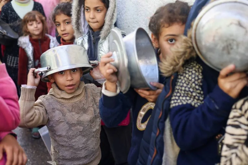 Palestinian children carry pots as they queue to receive food cooked by a charity kitchen, in Rafah in the southern Gaza Strip, on Thursday. REUTERS
