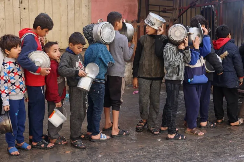 Palestinian children hold pots as they queue to receive food cooked by a charity kitchen, in Rafah in the southern Gaza Strip, on Thursday. REUTERS