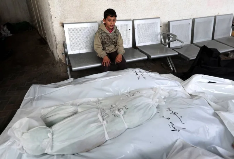A boy sits next to the bodies of Palestinians killed in Israeli strikes, in Rafah in the southern Gaza Strip, on Friday. REUTERS