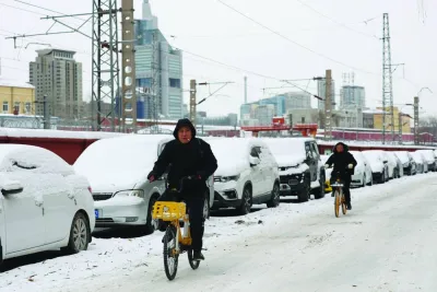 People ride bicycles on a road covered by snow following heavy snowfall in Beijing, China, yesterday. December