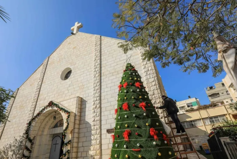 A man decorates a Christmas tree outside the Roman Catholic Church of the Holy Family in Gaza City on December 20, 2020, then closed to the public due to Covid-19 restrictions. A Christian mother and daughter were shot dead by an Israeli soldier on the grounds of the Catholic church in Gaza City on December 16, 2023, the Latin Patriarchate of Jerusalem said.  AFP