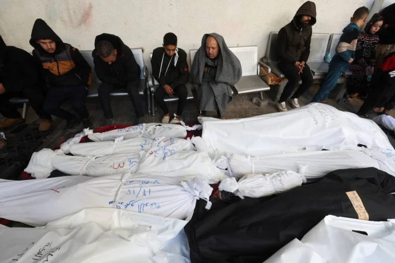 Mourners sit next to the bodies of Palestinians killed in Israeli strikes, at a hospital in Rafah, in the southern Gaza Strip, on Tuesday. REUTERS