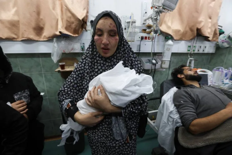 Mother of two Palestinian children, a newborn Al-Amera Ayesha and a young boy Ahmed Zourob, who were killed in an Israeli strike, holds her child next its wounded father, in Rafah, in the southern Gaza Strip, on Tuesday. REUTERS