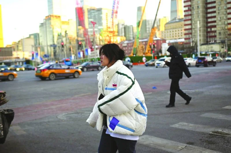 A woman crosses a street on a cold day in Beijing on Tuesday. A measure of foreign investment into China fell to the lowest in nearly four years in November, underlining how geopolitical tensions and a slowing economy have combined to convince foreign companies to slow their expansion.