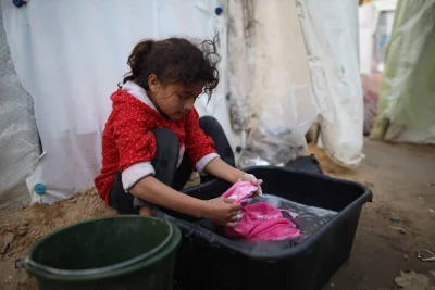 A displaced Palestinian girl hand-washes clothes in a tub near tent shelters around a hospital in Deir al-Balah in the central Gaza Strip following Israeli bombardment, on Friday. AFP