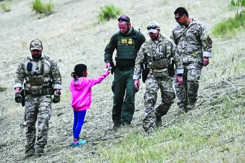 
A US Customs and Border Protection officer gives food to an immigrant child waiting to be processed at a US Border Patrol transit centre after crossing the border from Mexico at Eagle Pass, Texas. 