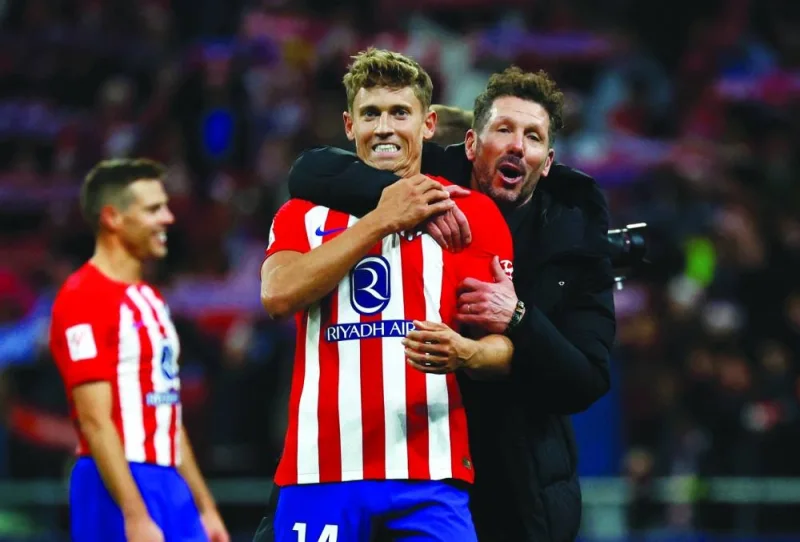 Atletico Madrid’s Marcos Llorente celebrates with coach Diego Simeone after the match. (Reuters)