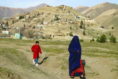 
An Afghan burqa-clad woman with a girl walks along a terrain in Fayzabad district of Badakhshan. (AFP) 