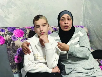 A recent photo shows 14-year-old Palestinian Abdelrahman al-Zaghal sitting next to his mother Najah as she talks, in their house in Jerusalem.