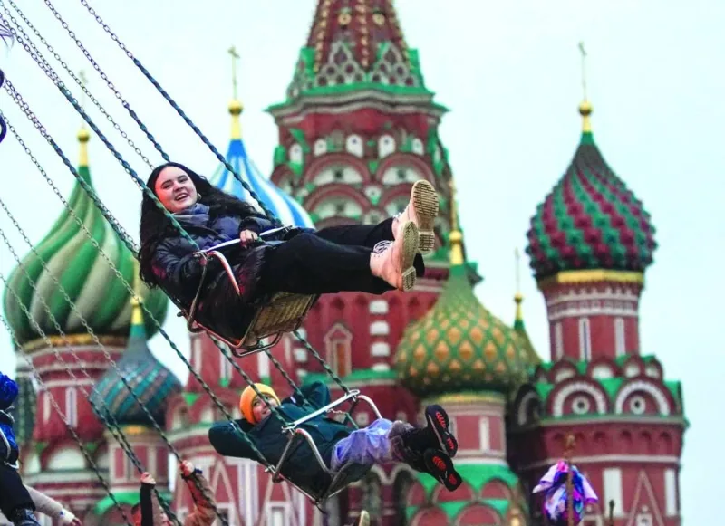 People enjoy a chain swing ride during the Christmas and New Year market in front of St. Basils cathedral on Red Square in Moscow on Saturday. (AFP)