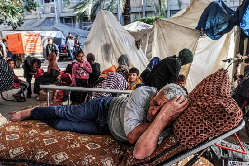 A man sleeps next to people sitting outside tents where displaced Palestinians are camped outside the European Hospital in Khan Yunis in the southern Gaza Strip, on Sunday. AFP