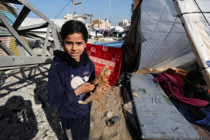 Muna Al-Sawaf, a displaced Palestinian girl from Gaza City, holds her cat as she stands outside her family tent in Rafah, southern Gaza Strip, on Sunday. REUTERS
