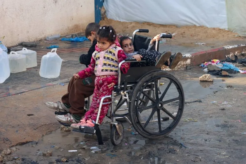 Palestinian children sit in a wheelchair while they make their way to collect water in Rafah, southern Gaza Strip, on Sunday. REUTERS
