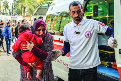 
A paramedic assists a woman carrying a child arriving at the European Hospital in Khan Yunis in the southern Gaza Strip, yesterday. 