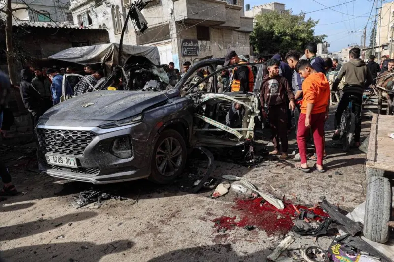 Palestinian civil defence members and onlookers gather around a car wreck following reported Israeli bombardment in Rafah in the southern Gaza Strip on on Monday. AFP