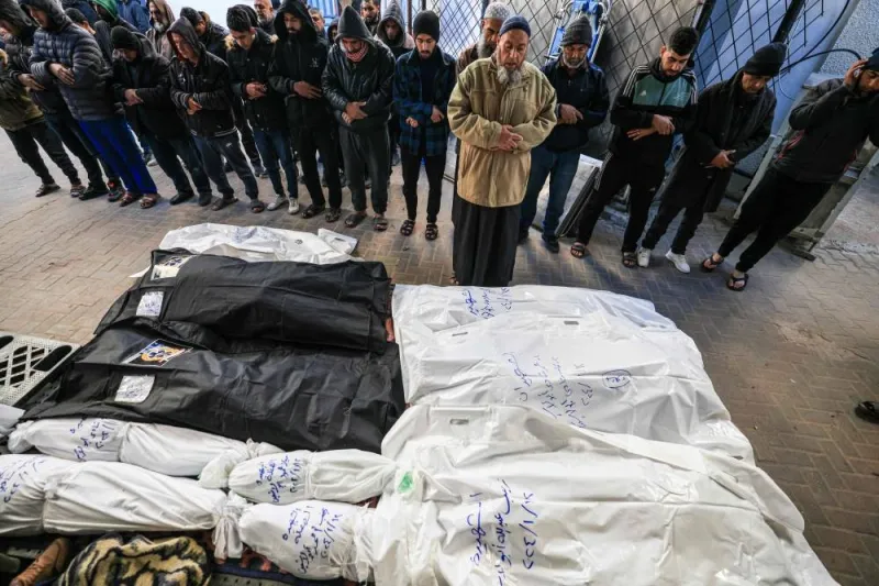 People pray over the shrouded bodies of loved ones killed during Israeli bombardment on Saturday, at the yard of a hospital in Rafah in the southern Gaza Strip. AFP