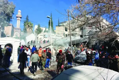 People and security forces gather in front of a building destroyed in an strike in Damascus.
