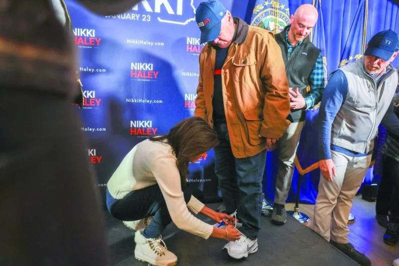 
Republican presidential candidate, ex-UN ambassador Nikki Haley, ties a man’s shoe after he arrives to greet her with an untied shoe during a campaign event held at Keene Country Club in Keene, New Hampshire. (AFP) 