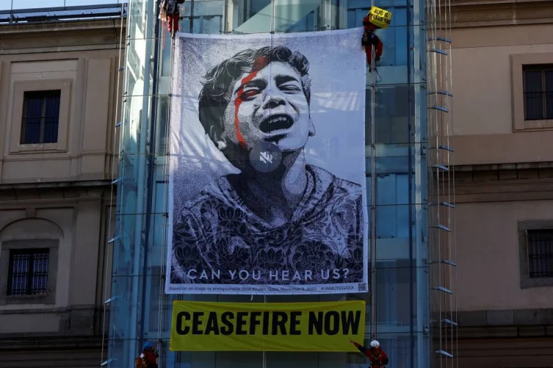 
Greenpeace activists unveil the illustration "Obey" by US artist Shepard Fairey, which depicts a photograph by Gazan photojournalist Belal Khaled of a Palestinian child crying for help, next to a banner reading: "Ceasefire now", outside Reina Sofia museum, home of Picasso’s "Guernica", in Madrid, Spain, on Wednesday. REUTERS