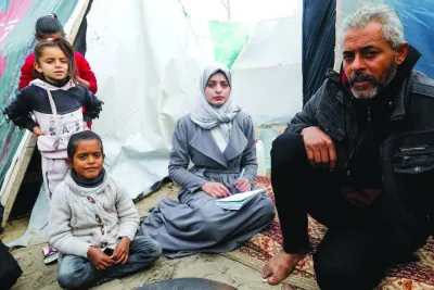 
Aseel Abu Haddaf (second right), a Palestinian medical student who fled her house in Khan Younis with her family due to Israeli strikes amid the ongoing conflict, looks on as she sits next to her father at a tent camp where they shelter, in Rafah in the southern Gaza Strip. 