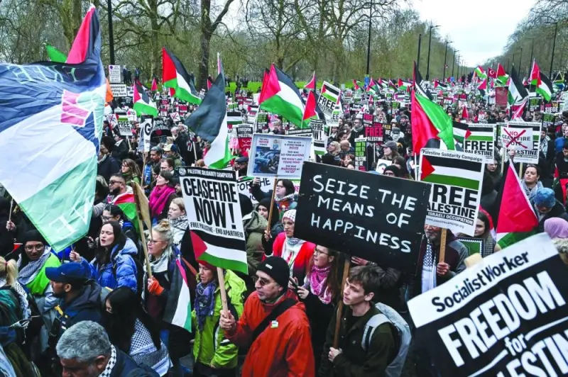 Pro-Palestinian activists and supporters wave flags and carry placards during a National March for Palestine in central London Saturday.