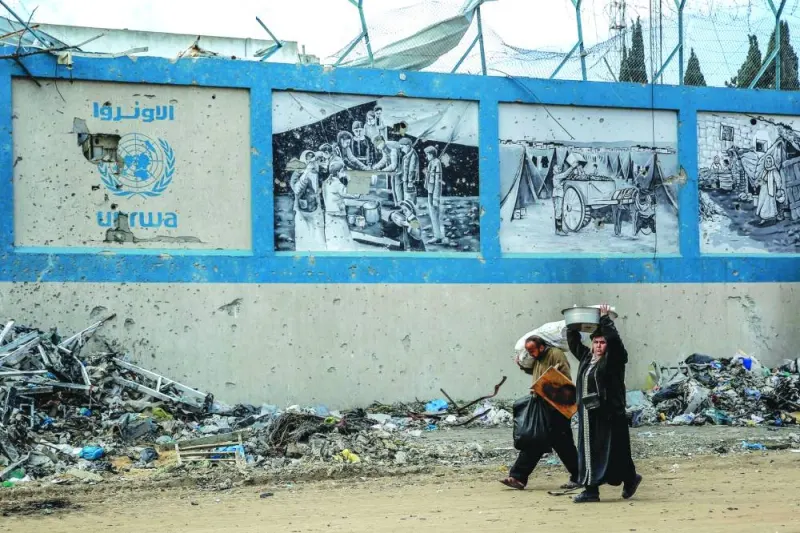
People walk past the damaged Gaza City headquarters of the UN Relief and Works Agency for Palestine Refugees (UNRWA), amid ongoing battles between Israel and  Hamas. 