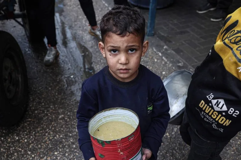 A displaced Palestinian child carries a ration of red lentil soup, distributed by volunteers in Rafah in the southern Gaza Strip on Sunday. AFP