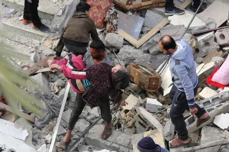 A man carries a girl pulled from the rubble of a house in Deir al-Balah in the central Gaza Strip after it was hit in an Israeli air strike Sunday.