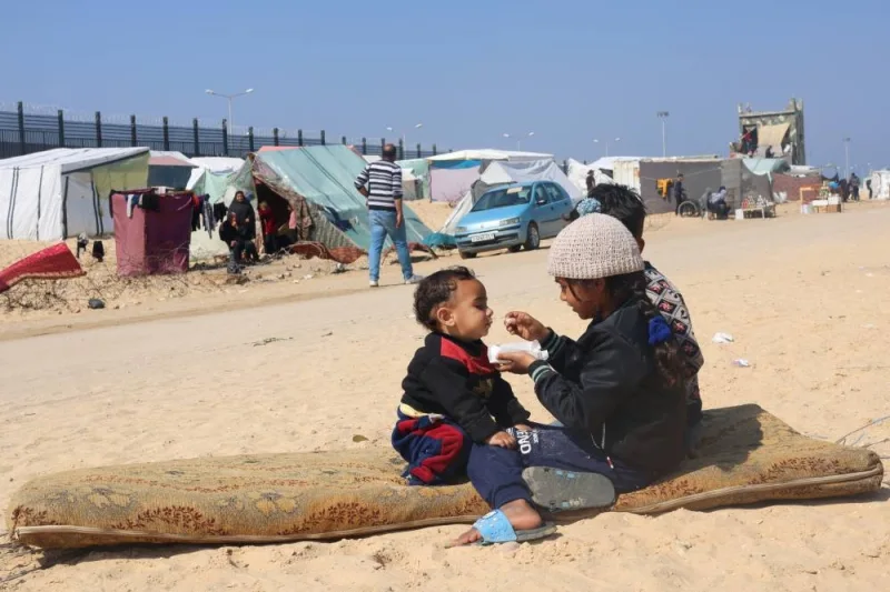 Displaced Palestinian girl, who fled her house due to Israeli strikes, feeds her brother at a tent camp, near the border with Egypt, in Rafah in the southern Gaza Strip, Sunday. REUTERS