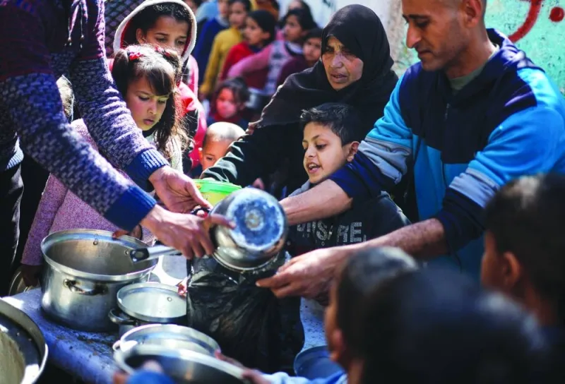 Palestinian children wait to receive food cooked by a charity kitchen in Rafah, Tuesday.