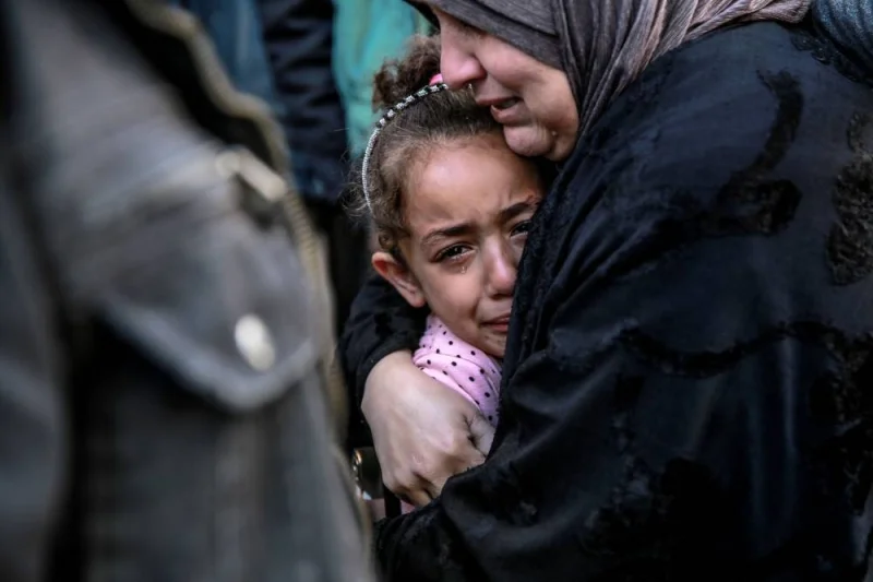 A Palestinian woman holds a child as they mourn their relatives killed in Israeli bombardment in front of the morgue of the Al-Shifa hospital in Gaza City on Friday. AFP