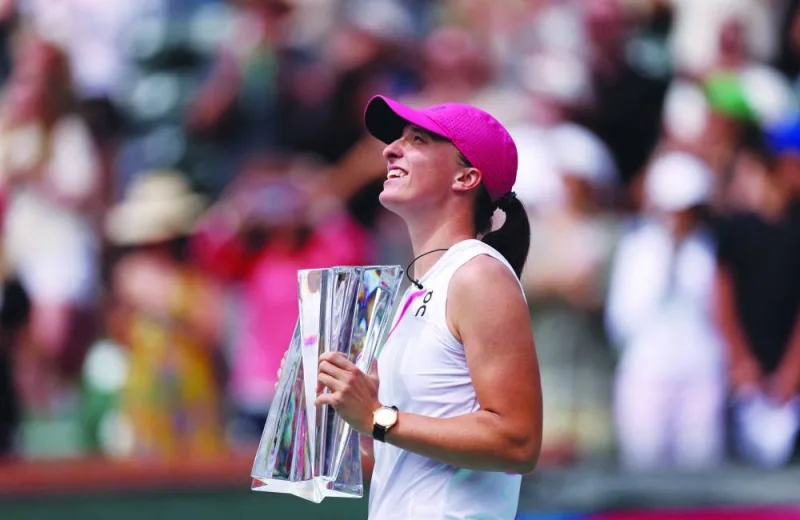 Iga Swiatek of Poland holds her winner&#039;s trophy after her straight-sets victory against Maria Sakkari of Greece in the final during the BNP Paribas Open at Indian Wells Tennis Garden in Indian Wells, California. (AFP)