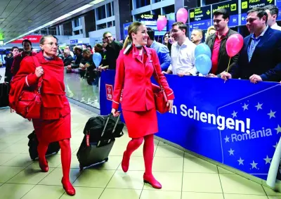 Flight attendants walk next to a banner reading 'Welcome to Schengen!' in Romania a few minutes after midnight, just after Romania's official entry into the European area of free circulation at Otopeni's 'Henri Coanda' international airport yesterday. (AFP)