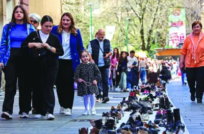 
People walk next to a ‘Memorial Lane’, comprising more than 15,000 pairs of shoes symbolising the residents of Sarajevo who were killed during the 1992-95 siege of the city, in Sarajevo. 