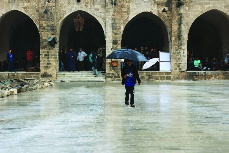 A Palestinian child walks with an umbrella under the rain in the courtyard of Gaza City's historic Omari Mosque, which has been heavily damaged in Israeli bombardment.