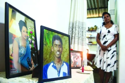 
Sriyani Sirimanna, wife of Sri Lankan government employee Saman Sirimanna is pictured at her house on the outskirts of Colombo, as she looks at photographs of their children Imash Thivanka (centre) and Medha Sathsarani (left), who lost their lives when a lone attacker hit St. Anthony’s church during the April 2019 massacre in Colombo. 