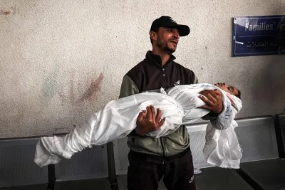 A Palestinian man holds the shrouded body of his child killed in Israeli bombing in Rafah in the southern Gaza Strip on Saturday. AFP