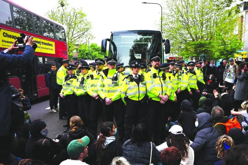 Metropolitan Police officers (MET) surround a bus reportedly waiting to remove migrants and asylum seekers from a hotel in Peckham, south London, as protesters gather to block it from transporting them to the Bibby Stockholm barge in Portland, Dorset, south-west England, on Thursday.