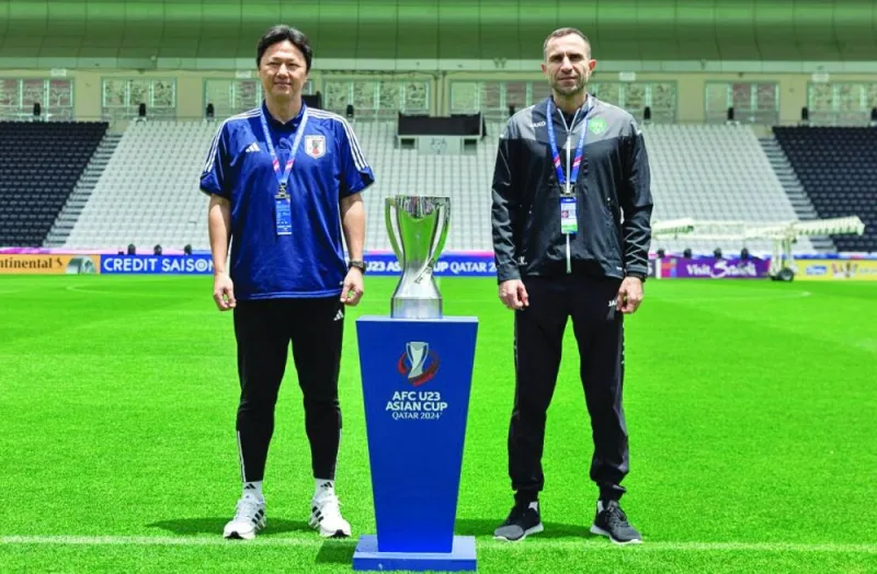 Uzbekistan’s coach Timur Kapadze (right) and his Japan counterpart Go Oiwa pose with the AFC U-23 Asian Cup trophy on Thursday, on the eve of the final at the Jassim Bin Hamad Stadium