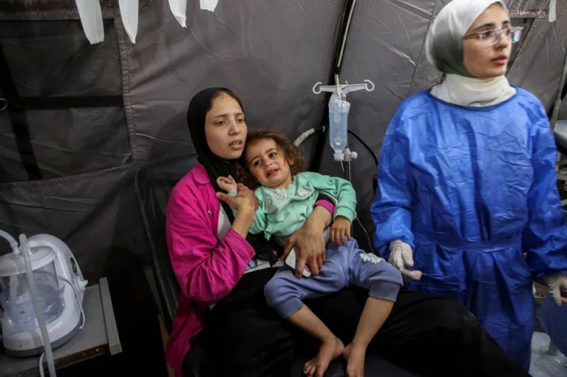 A Palestinian woman holds a girl wounded in an Israeli strike, at a hospital as Israeli forces launch a ground and air operation in the eastern part of Rafah in the southern Gaza Strip on Tuesday. (Reuters)