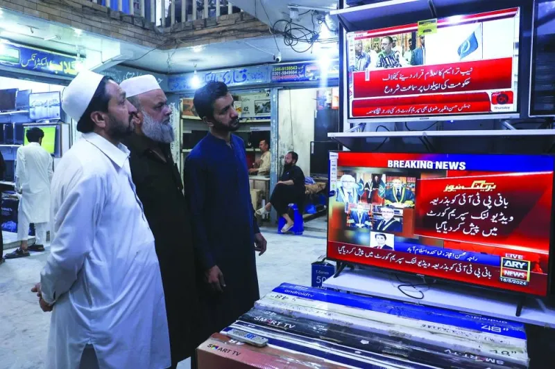 Men at a market in Peshawar watch television screens as they wait to see the appearance of the jailed former prime minister Imran Khan, which had been expected to be streamed live during a video proceeding of the Supreme Court of Pakistan.