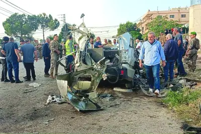 Lebanese army soldiers and onlookers gather around the remains of a car after it was hit by an Israeli strike, reportedly killing a local Hamas official, in Majd al-Jabal in Lebanon's Bekaa valley, yesterday.